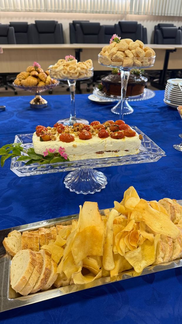 Coffee break com torta, frutas, pães e petiscos sobre toalha azul