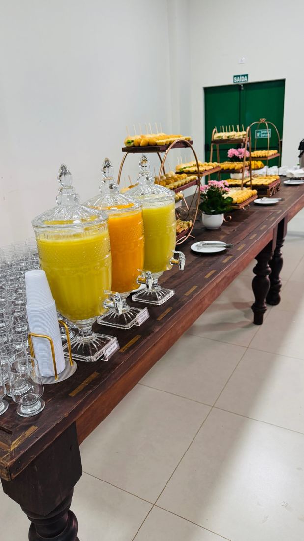Mesa de coffee break com sucos, pães e salgados em evento de empresa