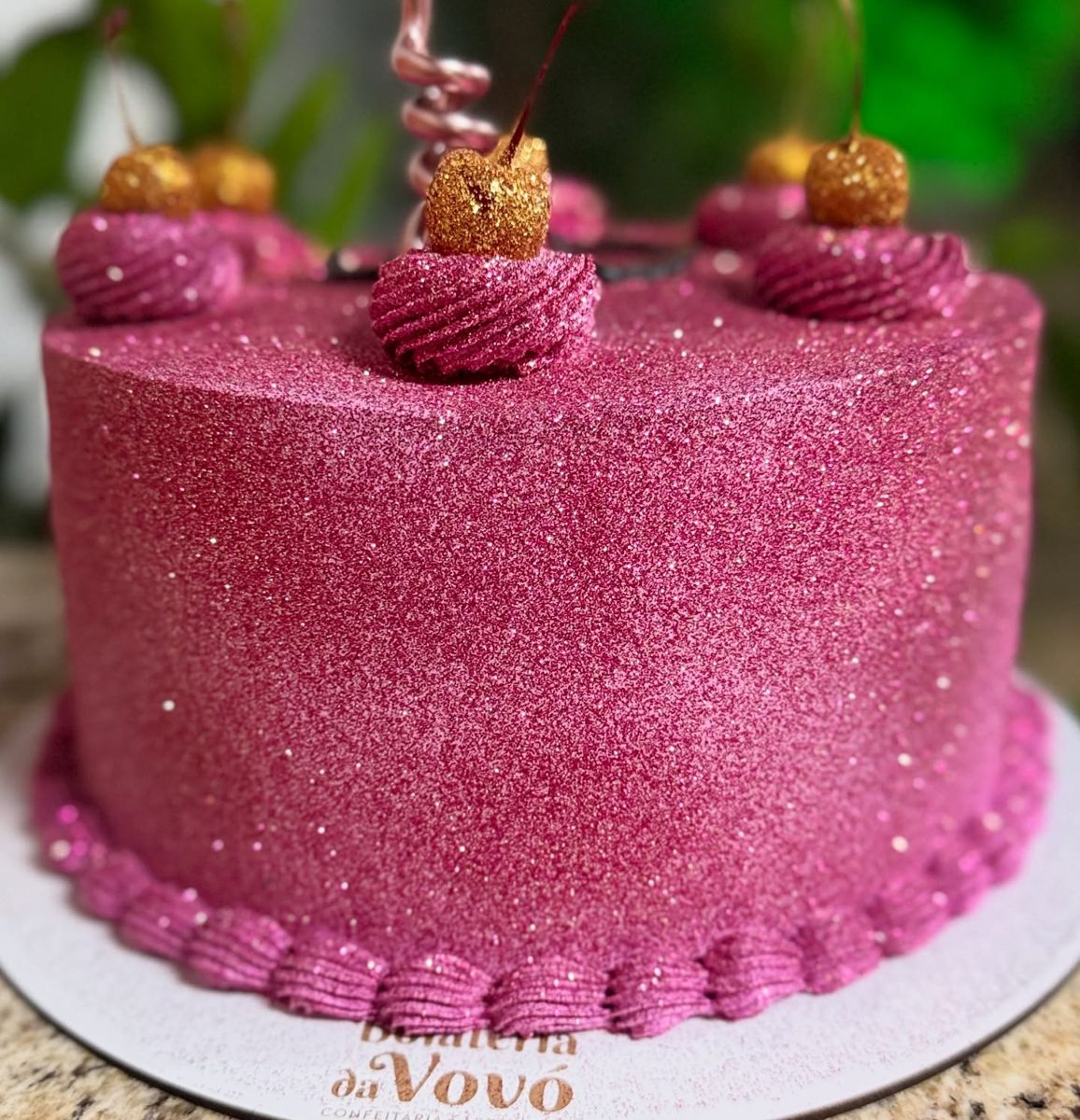Bolo rosa brilhante decorado com cerejas douradas