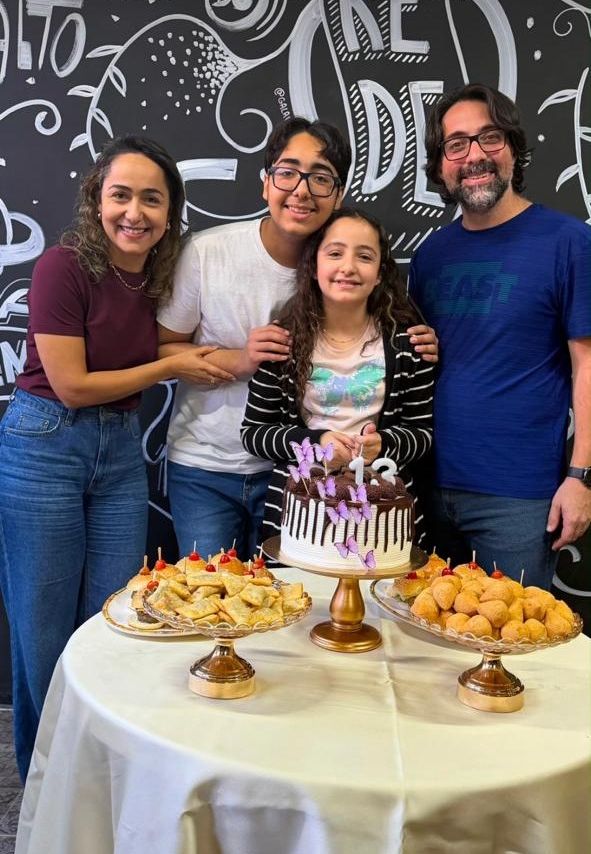 Família reunida em volta do bolo de aniversário e dos salgados