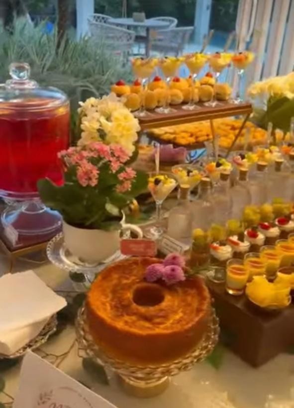 Mesa de celebração com bolo caseiro, flores e sobremesas